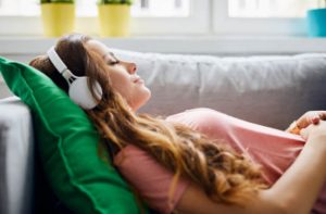 A woman with headphones laying down, listening to music
